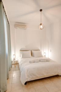 a white bedroom with a large bed with white sheets at Sugar Blue - Apartments on the beach in Áyios Vasílios