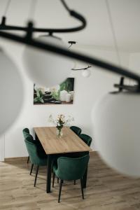uma sala de jantar com uma mesa de madeira e cadeiras verdes em SEVEN em Vinkovci