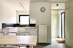 a kitchen with a table and a clock on the wall at De Woning, Wijk de Brabander 109 in Cadzand +11 photos