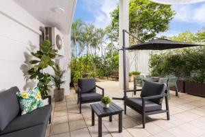 um pátio com cadeiras, um guarda-sol e uma mesa em Spacious 2 Bed/2 Bath Garden Apartment Aircon em Brisbane