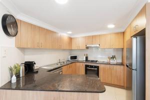 a kitchen with wooden cabinets and a stainless steel refrigerator at Spacious 2 Bed/2 Bath Garden Apartment Aircon in Brisbane