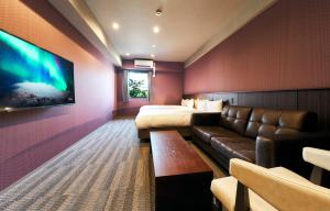 a hotel room with a couch and a bed and a tv at Rakuten STAY Kokura Station in Kitakyushu