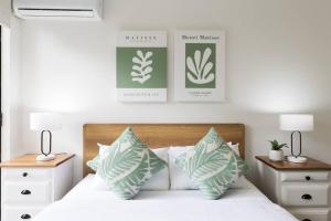 um quarto com uma cama com almofadas e cartazes na parede em Spacious 2 Bed/2 Bath Garden Apartment Aircon em Brisbane