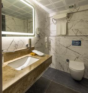 ein Badezimmer mit einem Waschbecken, einem WC und einem Spiegel in der Unterkunft Belenli Resort Hotel in Belek