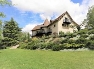 a house on a hill with a green lawn at Le gite de la tour in Bressieux
