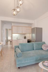 a living room with a blue couch and a kitchen at Sugar Blue - Apartments on the beach in Áyios Vasílios