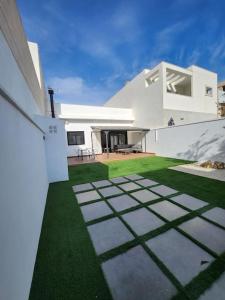 une maison blanche avec une cour avec de l'herbe verte dans l'établissement the butterfly house, à Rafelbuñol