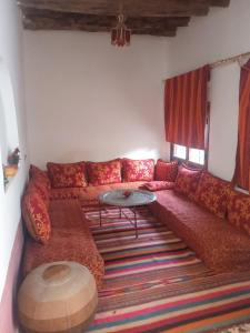 uma sala de estar com um sofá vermelho e uma mesa em Dar Es Salam em Skoura