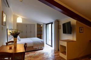 1 dormitorio con cama, mesa y TV en Charembeau en Forcalquier