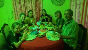 a group of people sitting around a table eating food at CAJANUS HOMESTAY in Karatu