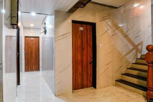 a hallway with two wooden doors and stairs at FabExpress Yatri Inn in Turambhe