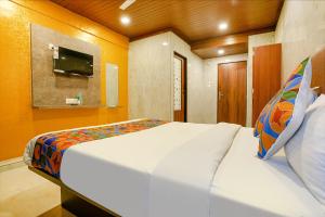 a bedroom with a large bed with a tv on the wall at FabExpress Yatri Inn in Turambhe