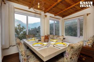 comedor con mesa y ventana grande en StayVista at Bird's Crest Valley Villa, en Rāmgarh