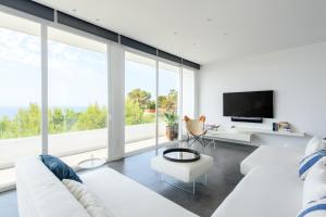 a living room with white furniture and large windows at Villa Nineten in Roca Llisa