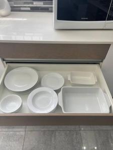 a drawer filled with white plates and a microwave at Gifty Surprize Airbnb in Kimberley