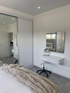 a white bedroom with a desk and a mirror at Gifty Surprize Airbnb in Kimberley