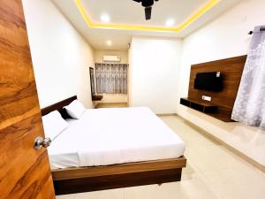 um quarto com uma cama e uma televisão na parede em Hotel Kutch Palace em Bhuj