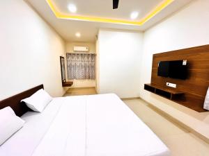 ein Schlafzimmer mit einem großen weißen Bett und einem TV in der Unterkunft Hotel Kutch Palace in Bhuj