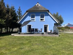 a blue house with a table and chairs in a yard at Ferienhaus De niege Leive in Born