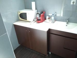 a microwave sitting on top of a sink in a bathroom at Privacidade na sua estadia no Centro do Montijo. in Montijo