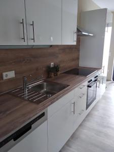 a kitchen with white cabinets and a stainless steel sink at Auszeit-Räumlichkeiten in Dietfurt +11 photos