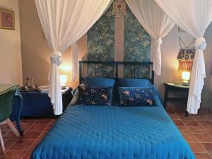 Schlafzimmer mit blauem Bett und Vorhängen in der Unterkunft Une chambre en Provence in Correns