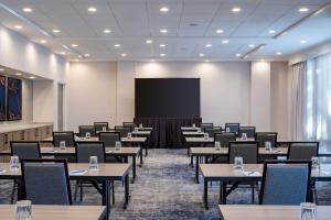 una sala de conferencias con mesas y una pantalla de proyección en Delta Hotels by Marriott Jacksonville Deerwood, en Jacksonville