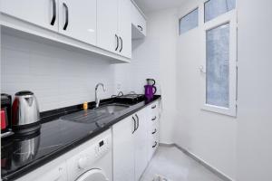 cocina blanca con fregadero y ventana en Cozy Flat 10 min to Marmaray and Uskudar Coast, en Estambul