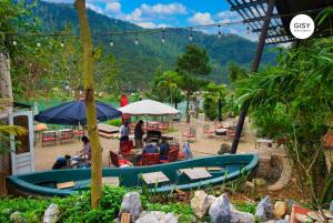 a group of people sitting in chairs under an umbrella at GISY Lake House in Sóc Sơn