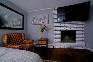 a bedroom with a fireplace and a chair and a tv at SHALIGOHOMES QUEEN SUITE ON 16TH in Anchorage