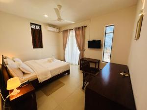 a bedroom with a bed and a desk and a television at Moi Hikka by DBI in Hikkaduwa