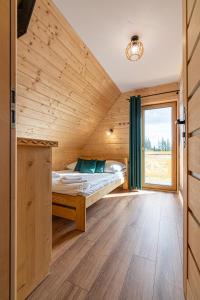a bed in a wooden room with a window at Domki Tatrzański Przystanek in Białka Tatrzańska