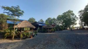 un edificio con un paraguas de paja y plantas delante de él en La plage by lee & hap guest house en Kampot