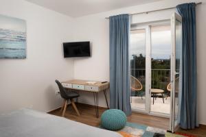 een slaapkamer met een bed, een bureau en een balkon bij Villa Oliva - Adriatic Luxury Villas in Murvica
