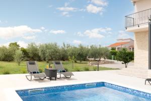 MurvicaにあるVilla Oliva - Adriatic Luxury Villasのラウンジチェア2脚付きのスイミングプールが隣接しています。