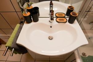 un lavabo blanc dans une salle de bain avec des tasses dessus dans l'établissement Transylvanian Hideaway Apartment, à Sibiu 14 autres photos