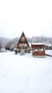 una cabaña de madera en la nieve con cenador en Vilat Pllumaj en Gropat e Selcës