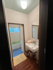 a bathroom with a sink and a shower and a mirror at 百合ヶ浜ビーチハウス in Furusato