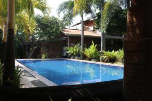 a swimming pool in front of a house with palm trees at Pavana Hotel in Negombo
