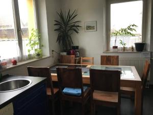 ein Esszimmer mit einem Tisch, Stühlen und Fenstern in der Unterkunft Pension Deinhardt in Hirschaid