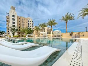 basen z białymi krzesłami i palmami w obiekcie Trophy - Blissful Haven with Breathtaking View w Dubaju