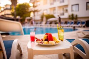 een fruitschaal op een tafel naast een zwembad bij Akalia Suite Hotel & SPA in Side