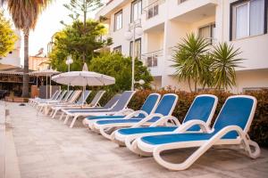 a row of blue and white lounge chairs next to a building at Akalia Suite Hotel & SPA in Side