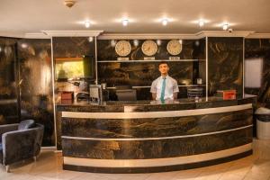 Un uomo in piedi dietro un bar nell'atrio di Akalia Suite Hotel & SPA a Side