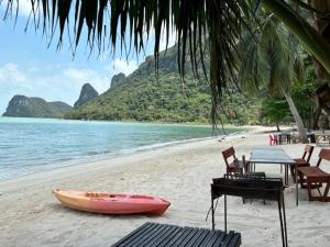 einen Tisch und ein Kajak am Strand in der Unterkunft Baan chidlomlay in Don Sak