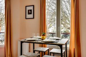 uma sala de jantar com uma mesa e uma grande janela em 145 Suite Marco - Superbe Appartement à Paris em Paris