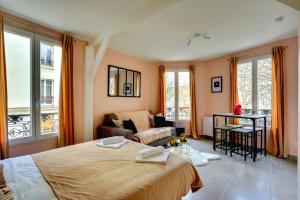 a bedroom with a bed and a couch and windows at 145 Suite Marco - Superbe Appartement à Paris in Paris