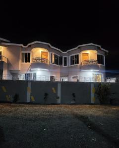 duży biały dom z oświetleniem w nocy w obiekcie OLENG'OTI GARDENS w mieście Narok