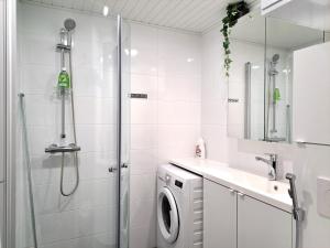 a bathroom with a shower and a washing machine at Kotimaailma Apartments - moderni keskustayksiö - Aleksanterinkatu in Tampere