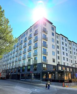 a large white building with the sun shining on it at Kotimaailma Apartments - moderni keskustayksiö - Aleksanterinkatu in Tampere